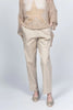 A person wearing Pablo Tricot Pants with Belt LX38551 and a beige mesh sweater featuring a large star design enjoys the comfort of their gold loafers. Made in Italy, this chic ensemble stands out against the light gray background, with hands casually resting in pockets.