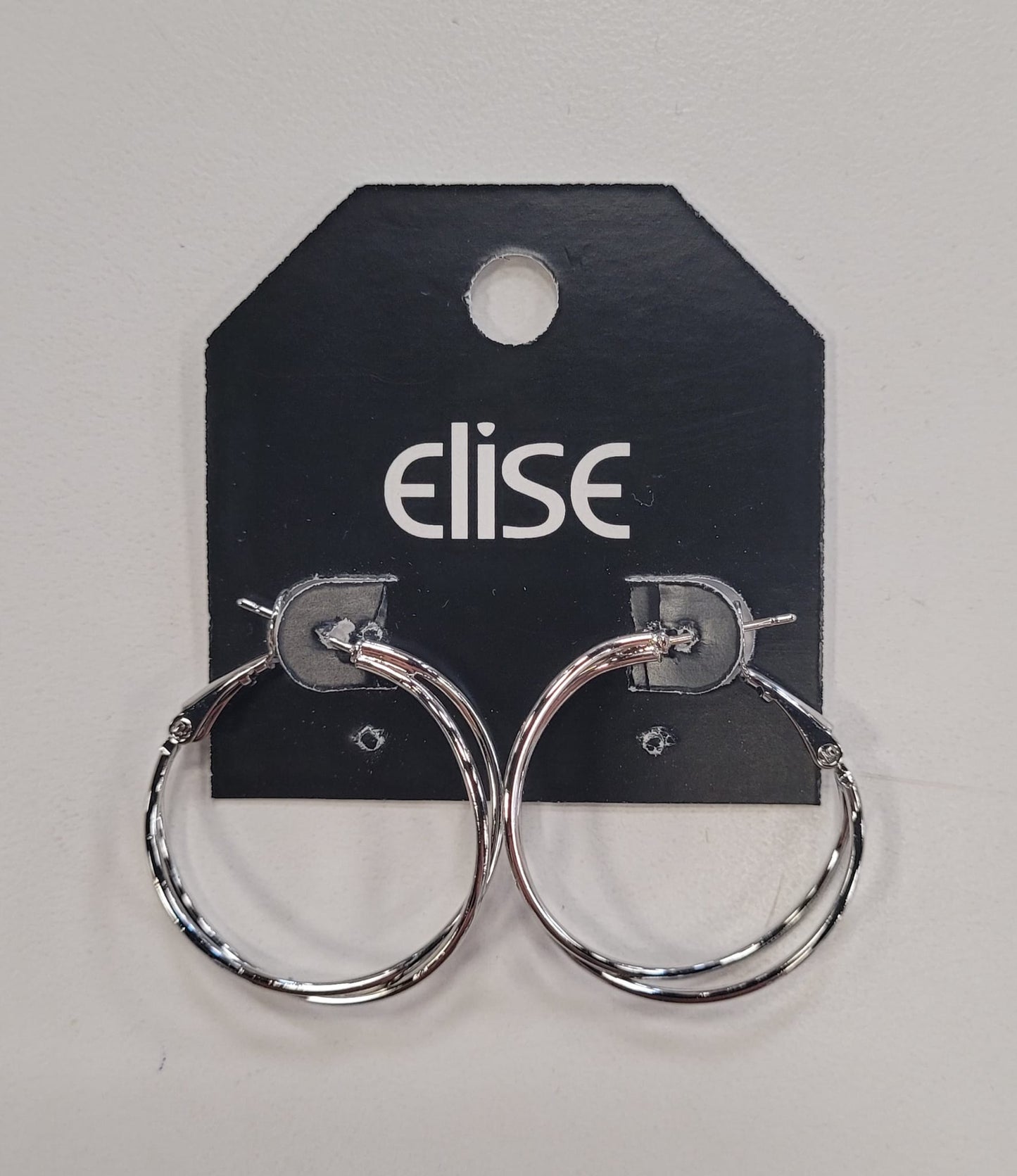 A pair of shiny silver Dana 81 Earrings by Elise accessories, displayed on a black Elise-branded card with a top hole against a light background—ideal for those who love classic gold and silver jewelry.