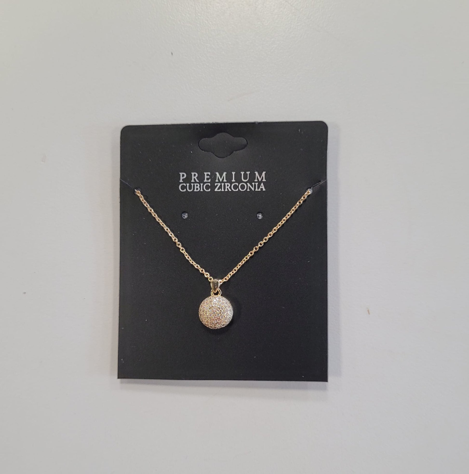 The Trina 8 Necklace by Elise accessories features a round pave pendant with cubic zirconia, displayed on a black card labeled "PREMIUM CUBIC ZIRCONIA," highlighting expert craftsmanship against a plain white background.