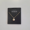 The Trina 8 Necklace by Elise accessories features a round pave pendant with cubic zirconia, displayed on a black card labeled "PREMIUM CUBIC ZIRCONIA," highlighting expert craftsmanship against a plain white background.
