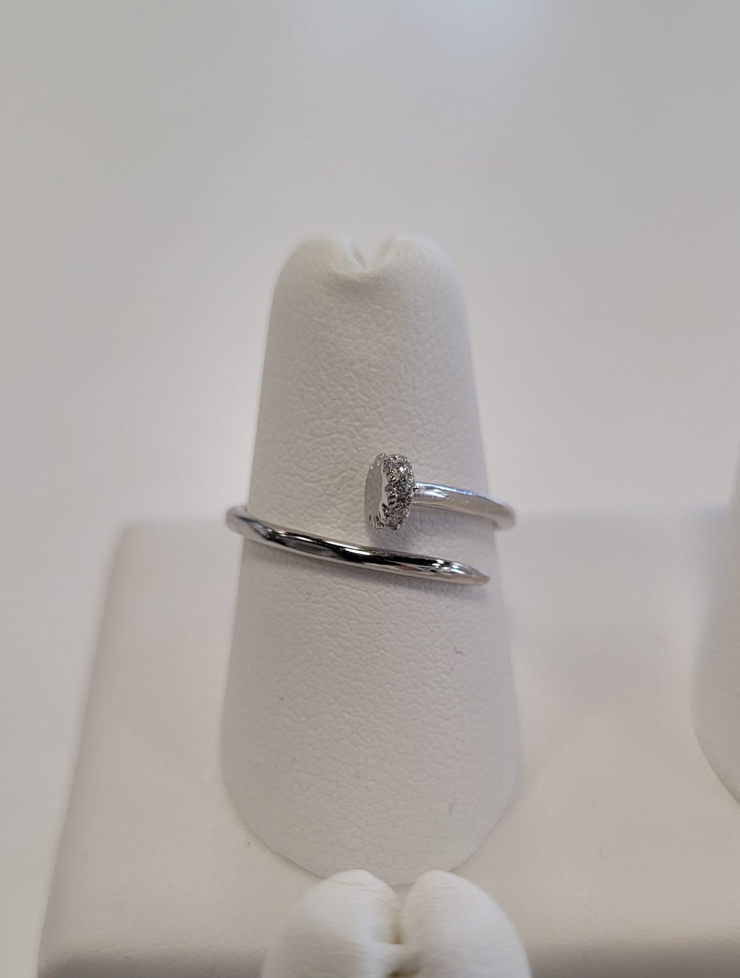 The Elisa 4 Ring by Elise Accessories is a minimalist sterling silver ring featuring an oval center detail, shown on a white ring holder with a soft, neutral background.