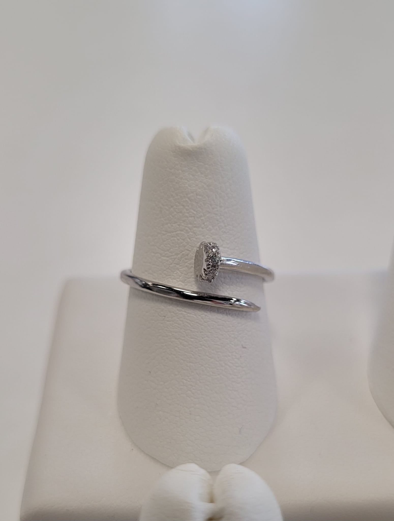 The Elisa 4 Ring by Elise Accessories is a minimalist sterling silver ring featuring an oval center detail, shown on a white ring holder with a soft, neutral background.