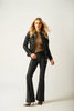 A woman with long blonde hair stands confidently in the MAURITIUS LEATHER Naemie RF Leather Jacket, styled with a brown top, black flared pants, and high heels against a simple light background.