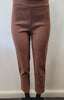 A person wearing Bali Corp's Classic Brown Pant—high-waisted, slim-fit ankle pants in polyester-spandex with button accents near the hem—stands against a plain white wall.