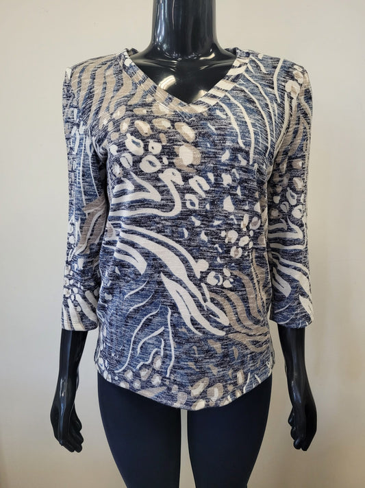 A mannequin showcases the Bali Corp Top-8677, a stylish long sleeve top with a V-neck and abstract white and blue swirling dotted patterns, set against a plain light background.