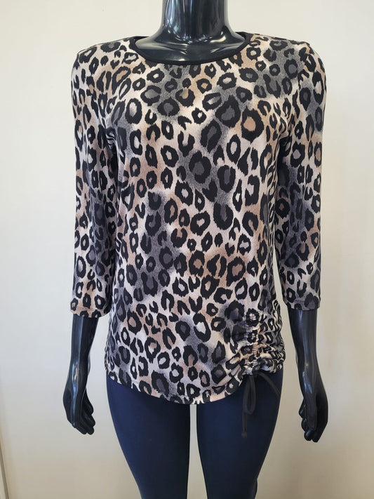 A mannequin models the Bali Corp Large Leopard Print Top -8735, featuring long sleeves, ruched sides with drawstrings, paired with dark pants against a plain background.