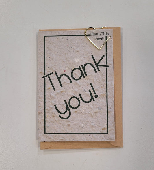 The Mini Greeting Card Seeded Memories by Seeded Memories is a recycled plantable card with "Thank you!" on it, clipped to a brown envelope with a gold heart paperclip. A note at the top says, "Plant This Card!" for an eco-friendly touch.