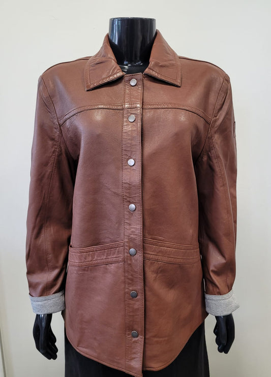 The Stevie CF Leather Jacket by MAURITIUS LEATHER, in brown cognac leather with a collar, button-down front, and large front pockets, is displayed on a black mannequin against a plain light background.