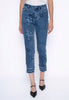A person stands against a plain white background wearing the Picadilly Frayed Hem Cropped Jean G6077GX with a floral and starburst pattern, paired with a white top and black pointed-toe heels.