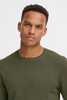 A young man with short curly hair wears the RAGWEAR Knitted Pullover 20718853 blend in olive green, looking directly at the camera with a neutral expression against a plain light background.