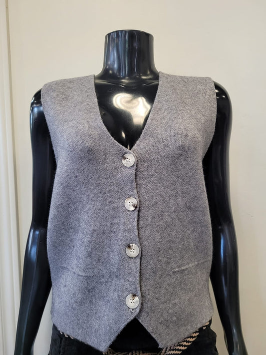 The ETERNELLE Button Up Knit Vest -eternelle is a sleeveless, light grey knit vest with four white front buttons, shown on a black mannequin against a plain background—a classic addition to any wardrobe.
