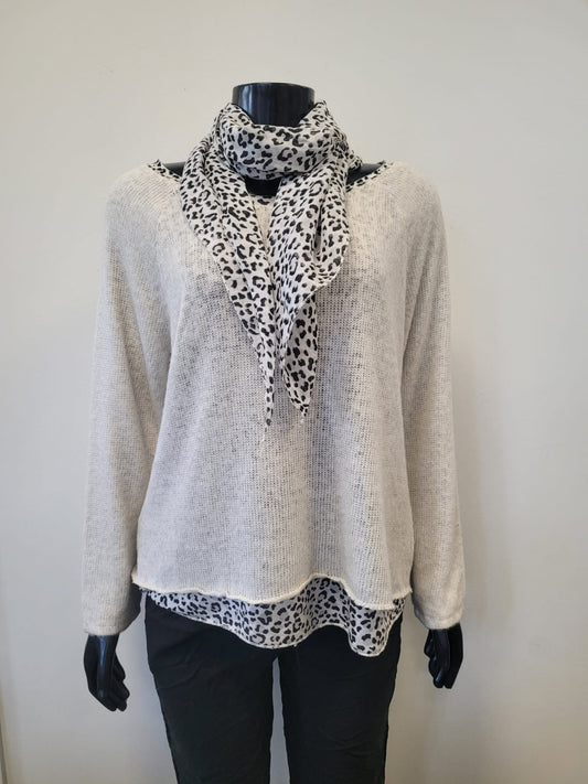 A mannequin showcases the ETERNELLE Leopard Print Accented Top layered over a beige knit, styled with black pants and an animal print scarf, set against a plain light background.