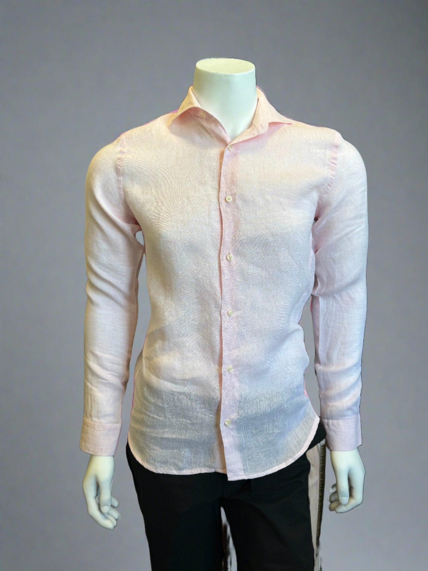 A mannequin is dressed in a slightly sheer, light pink Paul Miranda Linen Shirt Rosa paired with black pants. The 100% linen shirt by Paul Miranda, made in Italy, is fitted, highlighting the shape of the torso. The background is a plain grey shade.