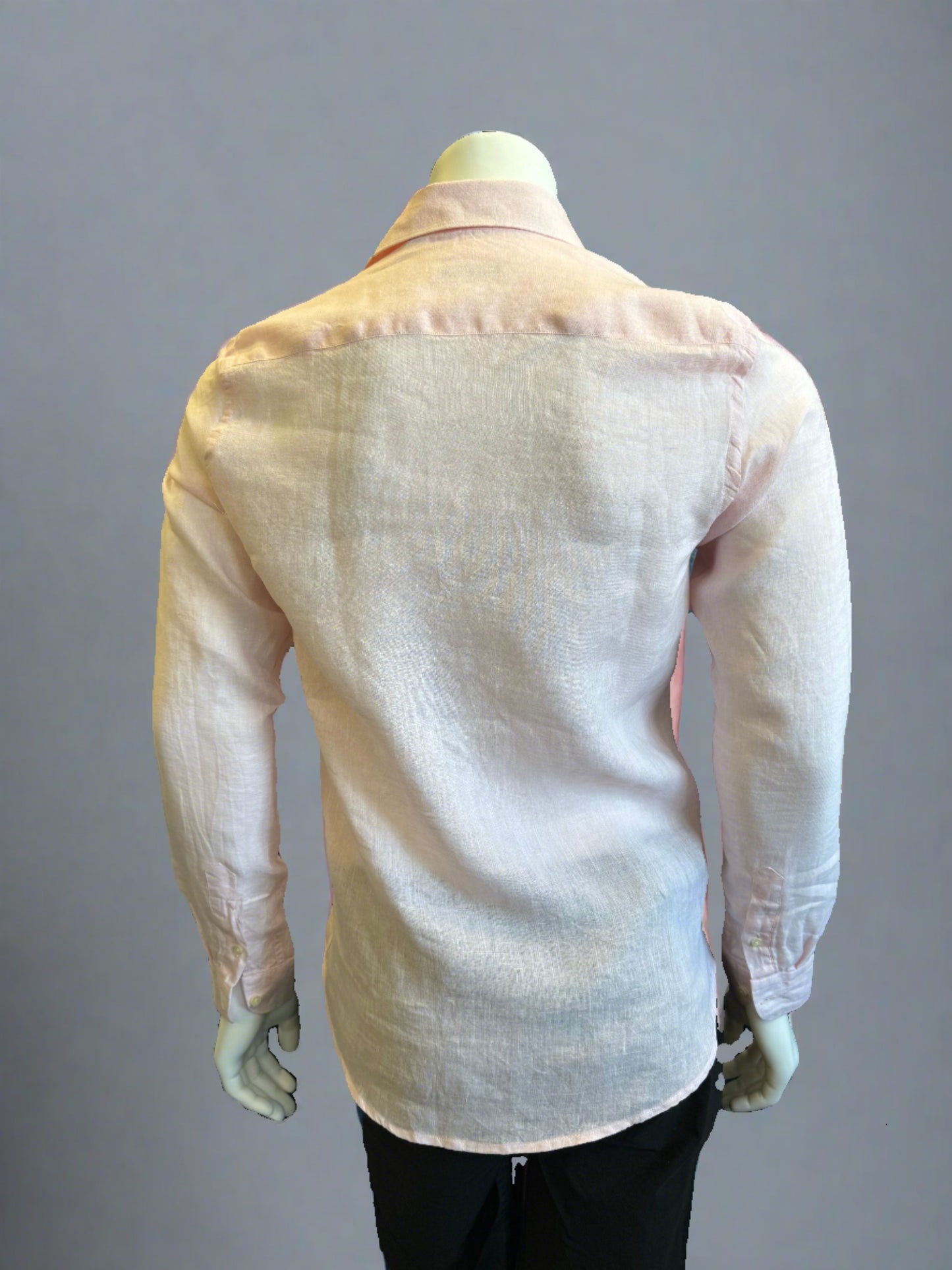 A mannequin is dressed in a slightly sheer, light pink Paul Miranda Linen Shirt Rosa paired with black pants. The 100% linen shirt by Paul Miranda, made in Italy, is fitted, highlighting the shape of the torso. The background is a plain grey shade.