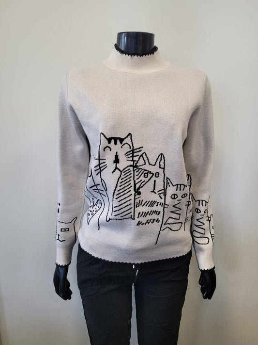 A mannequin models the ETERNELLE Knit Cat Lady Sweater -eternelle, featuring black abstract cat designs and black trim at the neck and cuffs, stylishly paired with black pants.