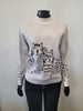 A mannequin models the ETERNELLE Knit Cat Lady Sweater -eternelle, featuring black abstract cat designs and black trim at the neck and cuffs, stylishly paired with black pants.