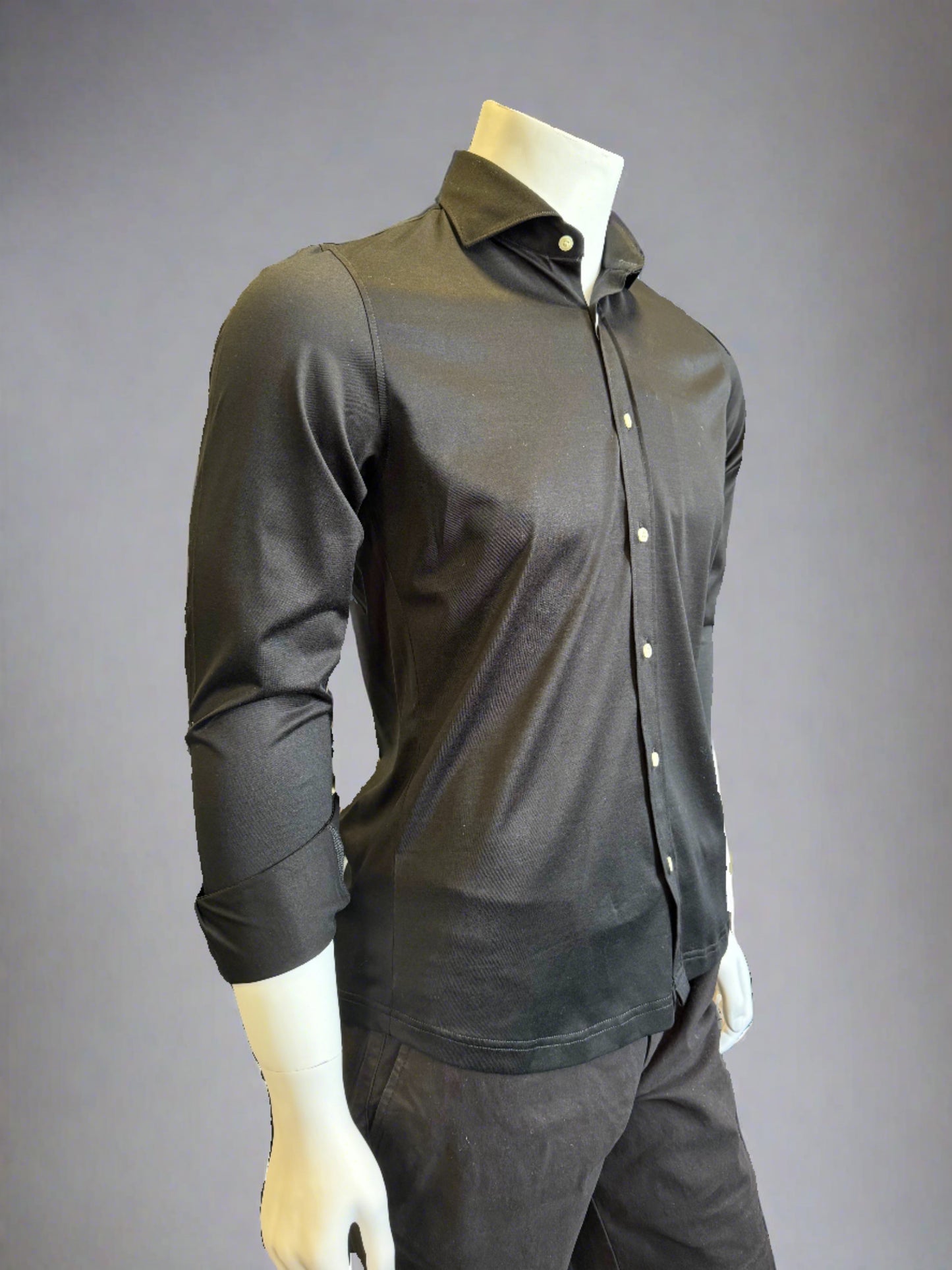 Introducing the Paul Miranda Cotton Shirt Black displayed on a white mannequin torso. This black, long-sleeve button-up shirt from Paul Miranda has a slight sheen and is fully buttoned, paired perfectly with matching black pants. The ensemble is set against a plain, gray background, exuding classic elegance.