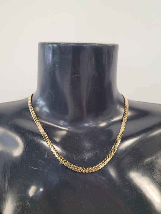 The Rhea-22 Necklace by Elise Accessories, a gold herringbone chain, is showcased on a glossy black mannequin bust set against a simple light background.