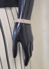 A mannequin hand displays the Mimosa 19 Bracelet by Elise accessories, its rhinestones sparkling against a black and white vertically striped skirt.