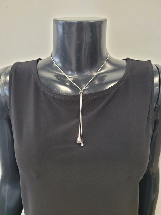 The Cadence-7 Necklace by Elise accessories, a silver drop slider necklace with teardrop-shaped ends, is shown on a black mannequin torso wearing a sleeveless black top.