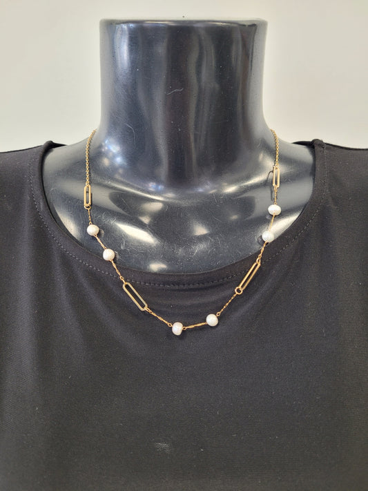 The Elena-4 Necklace by Elise accessories is a gold paperclip link chain with alternating pearls, shown on a black mannequin bust in a black top for a chic, modern look.