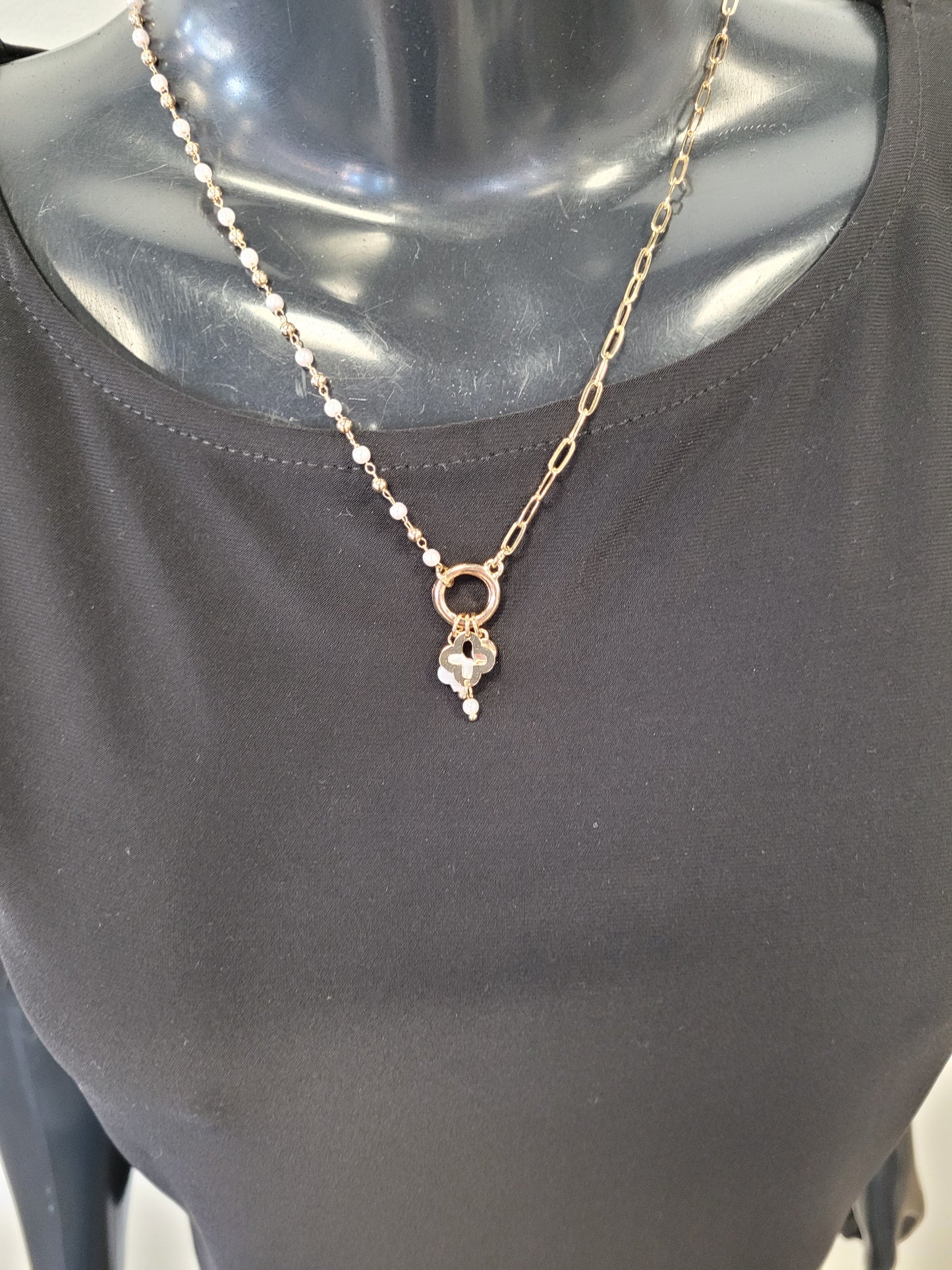 A mannequin in a plain black top showcases the Elena Necklace from Elise accessories, featuring a gold chain and a pendant with a delicate flower and pearl-like detail.