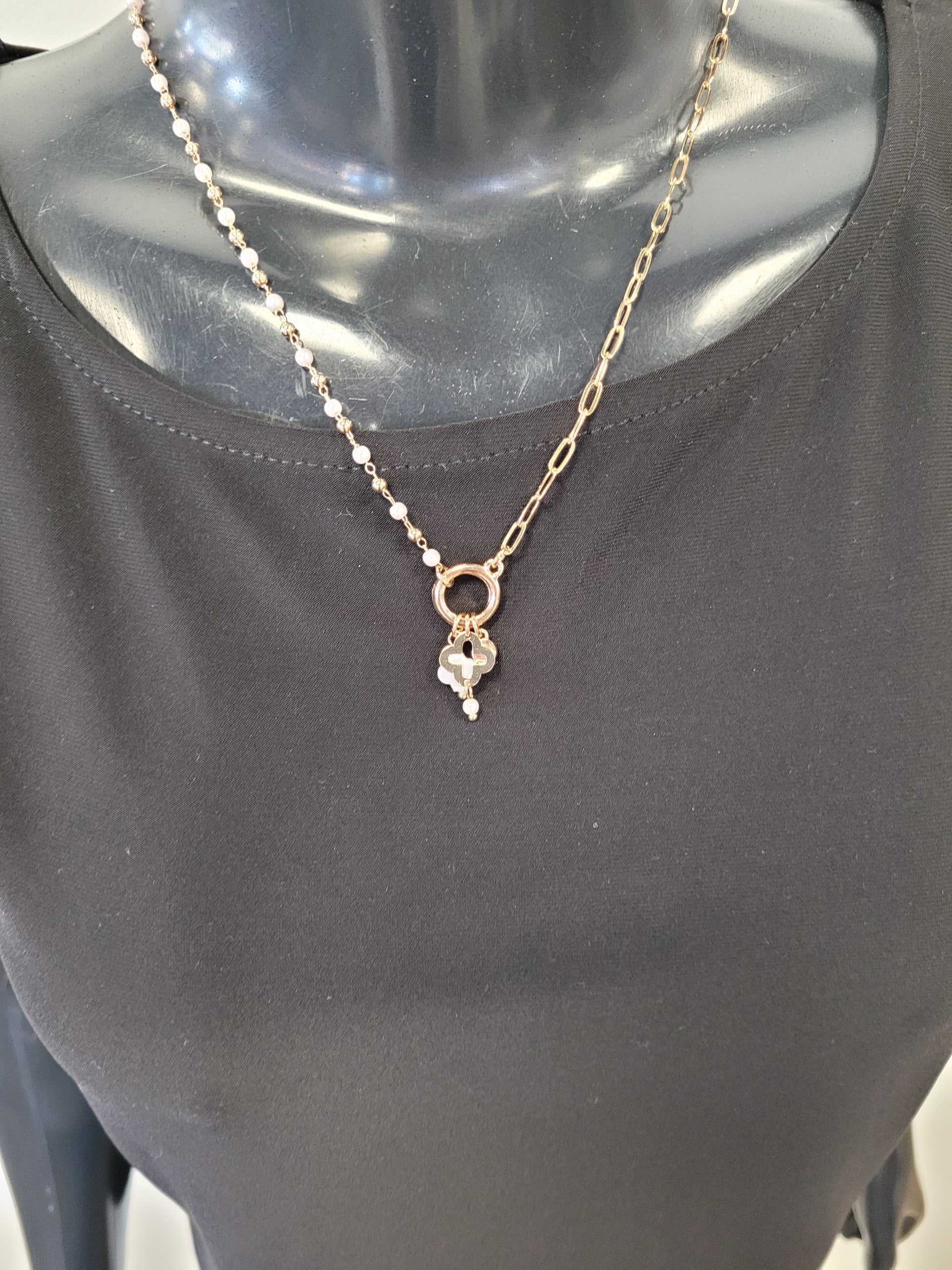 A mannequin in a plain black top showcases the Elena Necklace from Elise accessories, featuring a gold chain and a pendant with a delicate flower and pearl-like detail.