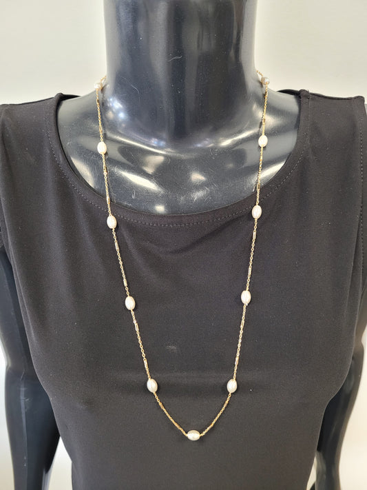 A mannequin in a black top showcases the Fiona-25 Necklace by Elise accessories, a timeless piece featuring stationed pearls along a long gold chain.