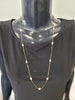 A mannequin in a black top showcases the Fiona-25 Necklace by Elise accessories, a timeless piece featuring stationed pearls along a long gold chain.