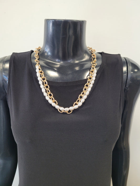 A black mannequin wears a sleeveless black top and the Elise accessories Roxanne-37 Necklace, a layered chain link piece with gold accents and white pearls, set against a plain light background.
