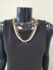 A black mannequin wears a sleeveless black top and the Elise accessories Roxanne-37 Necklace, a layered chain link piece with gold accents and white pearls, set against a plain light background.