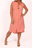 A person wears the Catherine Lillywhite Linen Sleeveless Dress (ITSM6428CO), a knee-length coral piece accented with a single button at the collar. They're posing with one hand on their hip, wearing beige sandals against a white background, exuding effortless elegance. Made in Italy.