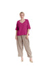 Against a white backdrop, a person dons the ERIN FUCHSIA TOP by Oh My Gauze with loose beige pants and matching shoes. The sweetheart neckline exudes charm as they look towards the camera, hair tied back and expression neutral.