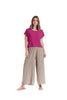 A woman stands against a white background in the OLGA FUCHSIA TOP from Oh My Gauze paired with beige wide-leg, cotton gauze Kate pants featuring side button details. She wears flat sandals and strikes a relaxed pose.
