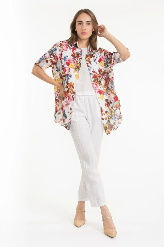 A woman models the LinenLuv French Linen Shirt TP1627-11 Bianco over a white top and pants, striking a pose against a white backdrop. Beige heels complement her chic look, while the eco-friendly natural European linen enhances her style.
