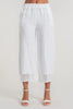 A person wearing LinenLuv's French Linen Pant PT840-11 Bianco, showcasing eco-friendly white linen with crochet cuff details, stands against a neutral background. The pants feature an elastic waistband and are paired with white open-toed heels.