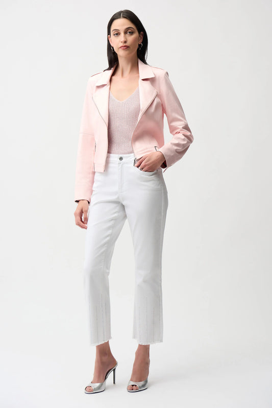 A woman stands against a plain background wearing the Joseph Ribkoff Foiled Faux Suede Fitted Jacket with Decorative Buckles 261910 in light pink, paired with a matching top, white cropped pants, and silver heels. She has straight dark hair and a neutral expression.