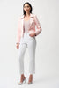 A woman stands against a plain background wearing the Joseph Ribkoff Foiled Faux Suede Fitted Jacket with Decorative Buckles 261910 in light pink, paired with a matching top, white cropped pants, and silver heels. She has straight dark hair and a neutral expression.