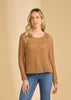 A woman with long blonde hair wears the French Dressing Jeans Long Sleeve Bubble Top in Henna and blue jeans, standing against a beige background.