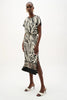 A woman models the Joseph Ribkoff Recycled Woven Animal Print Straight Skirt 262050, styled with black and white heeled sandals and gold hoop earrings, standing against a plain white background.