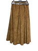 91208B FLARED VELVET SKIRT WITH BUCKLE BELT in camel by LINEN & COTTON HOUSE is a pleated midi skirt, reminiscent of a classic style, featuring a wide black belt with a gold buckle. It is displayed hanging on a hanger against a white background.