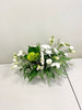 Refined Whites by Posies Flowers & Fashion is an elegant floral arrangement, showcasing white carnations and bellflowers complemented by green hydrangea and assorted greenery, all presented in a sleek white rectangular container. The arrangement is set on a plain white surface against a light-colored wall.
